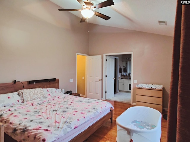 bedroom with vaulted ceiling, ceiling fan, connected bathroom, and hardwood / wood-style floors