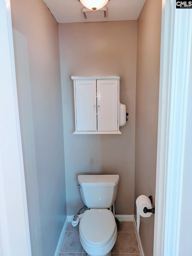 bathroom with toilet, tile patterned flooring, and a textured ceiling