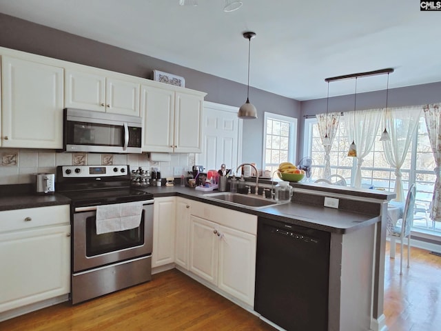 kitchen featuring white cabinetry, stainless steel appliances, kitchen peninsula, and sink