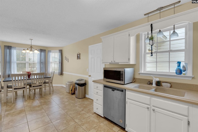 kitchen featuring hanging light fixtures, appliances with stainless steel finishes, sink, and white cabinets