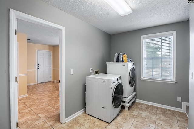 laundry room featuring light tile patterned floors, washer and dryer, and a textured ceiling