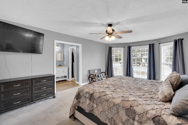 carpeted bedroom with ceiling fan, ensuite bath, and a textured ceiling