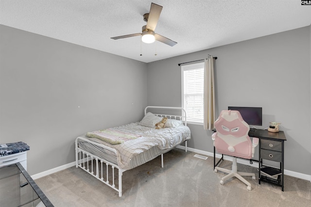 bedroom with ceiling fan, carpet flooring, and a textured ceiling