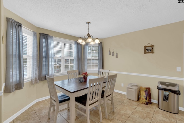 tiled dining room featuring a wealth of natural light, a textured ceiling, and an inviting chandelier