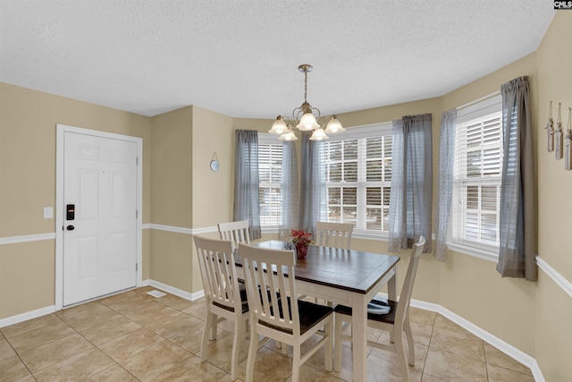 tiled dining area featuring an inviting chandelier, a wealth of natural light, and a textured ceiling