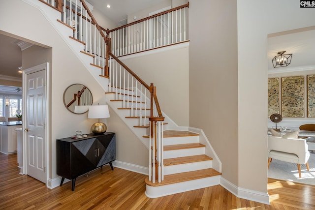 staircase featuring crown molding, wood-type flooring, and a chandelier