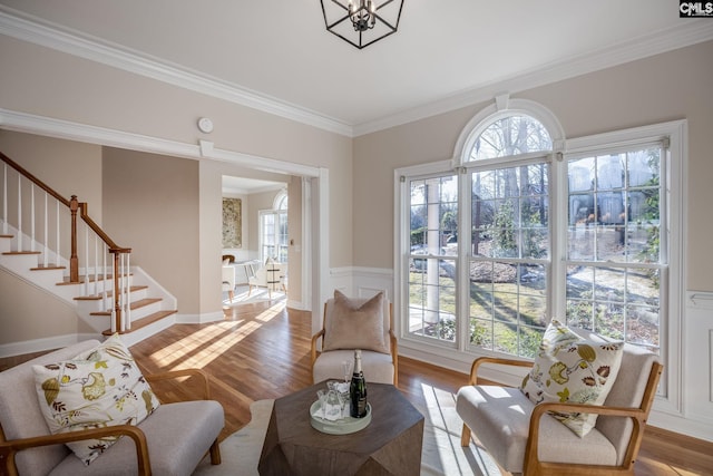 interior space featuring a healthy amount of sunlight, ornamental molding, hardwood / wood-style floors, and a notable chandelier