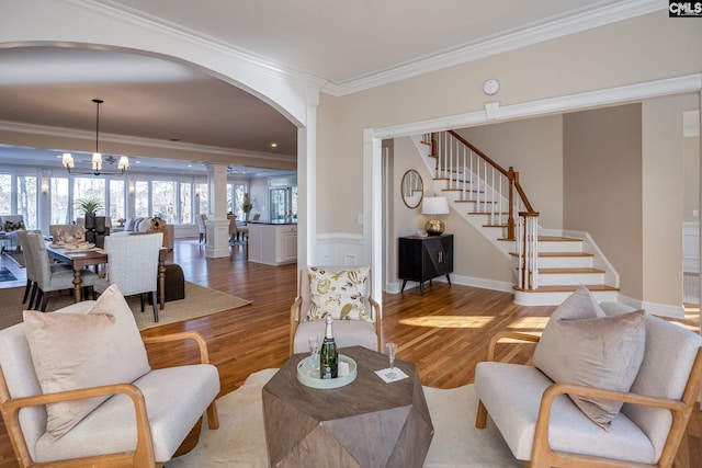 living room featuring hardwood / wood-style floors, a notable chandelier, ornamental molding, and ornate columns