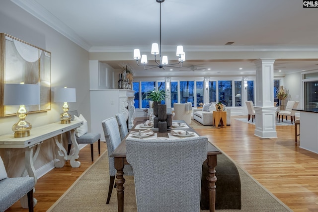 dining room featuring ornamental molding, a chandelier, decorative columns, and light wood-type flooring