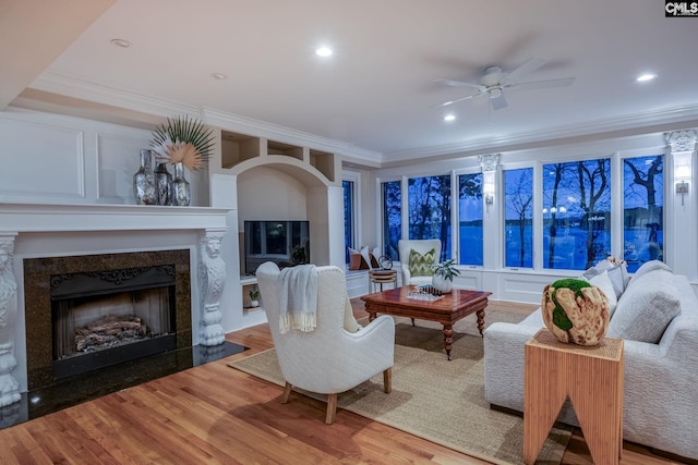 living room featuring hardwood / wood-style floors, a fireplace, ornamental molding, and ceiling fan