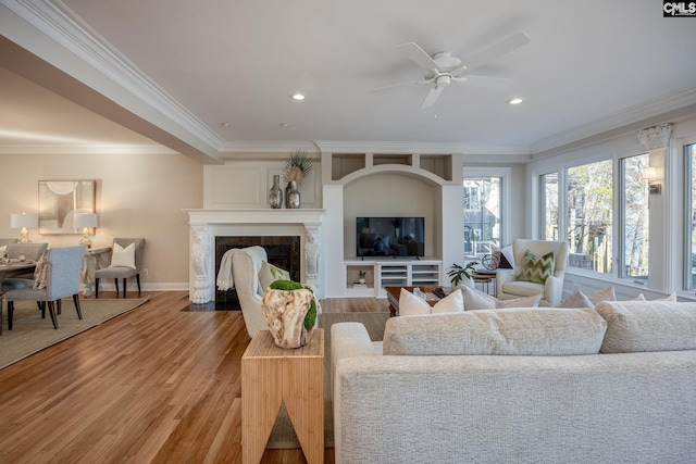 living room with hardwood / wood-style flooring, a fireplace, ornamental molding, and ceiling fan