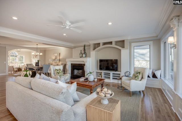 living room featuring a high end fireplace, light hardwood / wood-style flooring, ornamental molding, and a healthy amount of sunlight