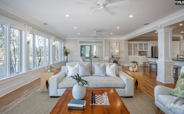 living room featuring ornamental molding, decorative columns, light hardwood / wood-style floors, and ceiling fan