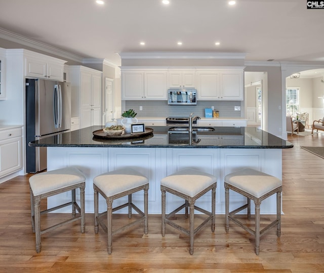 kitchen featuring white cabinetry, appliances with stainless steel finishes, sink, and a large island with sink