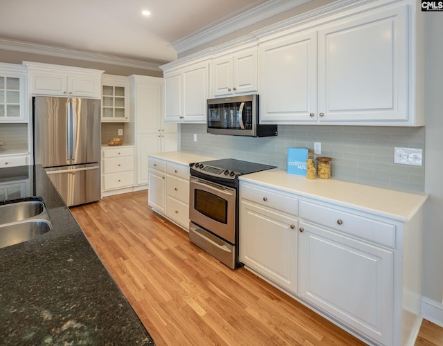 kitchen featuring ornamental molding, appliances with stainless steel finishes, decorative backsplash, and white cabinets