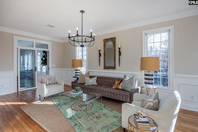 living room featuring hardwood / wood-style floors, crown molding, and a notable chandelier