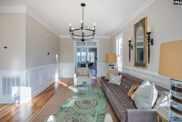 living room with hardwood / wood-style flooring, ornamental molding, and a chandelier