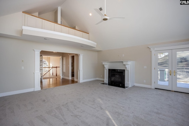 unfurnished living room featuring ceiling fan, high vaulted ceiling, carpet floors, french doors, and ornate columns