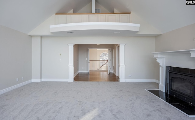 unfurnished living room with carpet flooring, a fireplace, high vaulted ceiling, and ornate columns