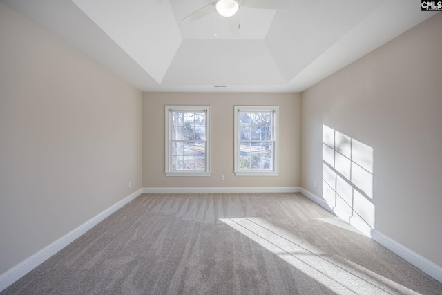 carpeted empty room featuring ceiling fan and a raised ceiling