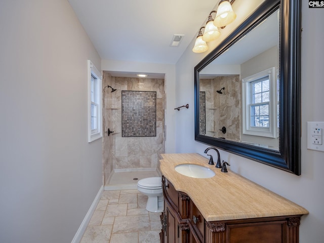 bathroom featuring a tile shower, vanity, and toilet