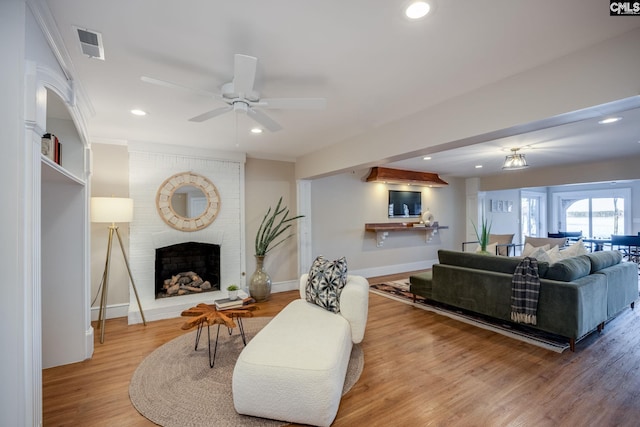 living room with hardwood / wood-style floors, a fireplace, and ceiling fan