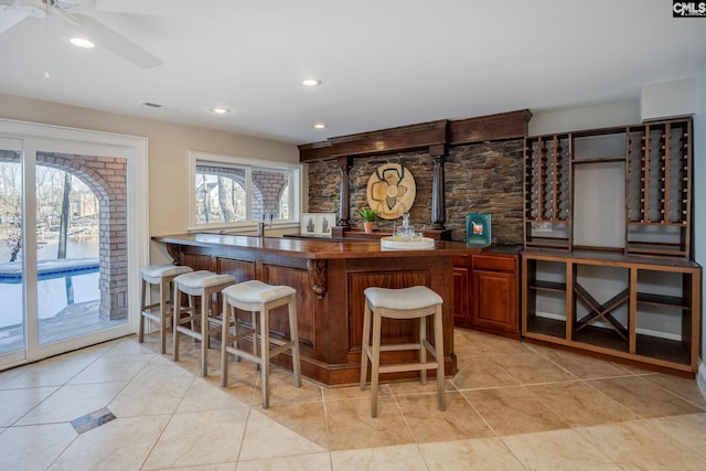 bar with ceiling fan, a healthy amount of sunlight, and light tile patterned flooring