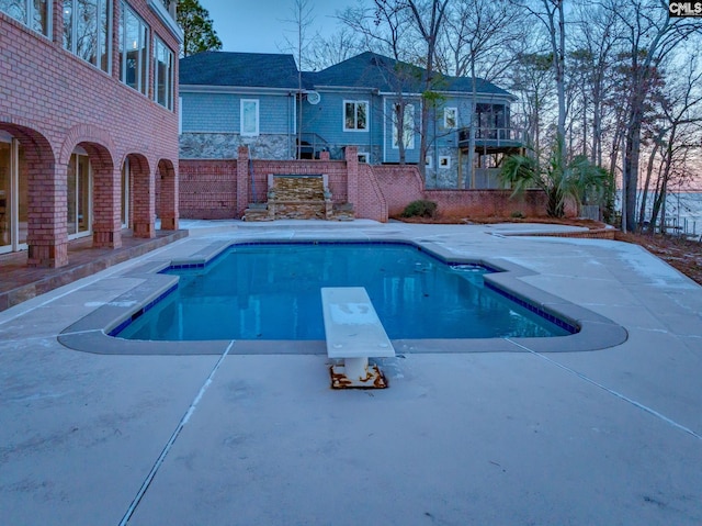 view of swimming pool with a patio and a diving board