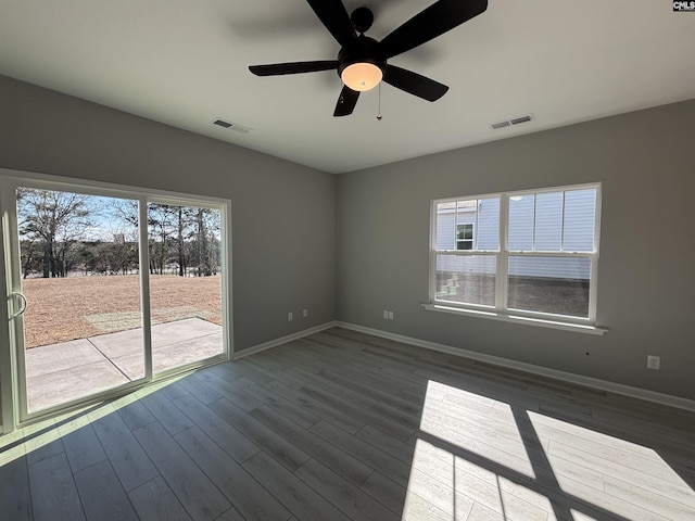 unfurnished room with a ceiling fan, visible vents, baseboards, and wood finished floors