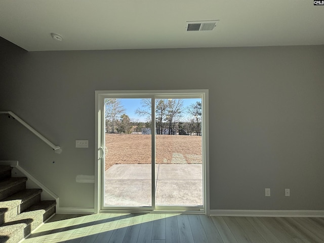 doorway featuring stairway, baseboards, visible vents, and wood finished floors