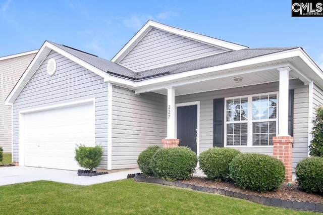 view of front of property featuring a garage, covered porch, and a front lawn