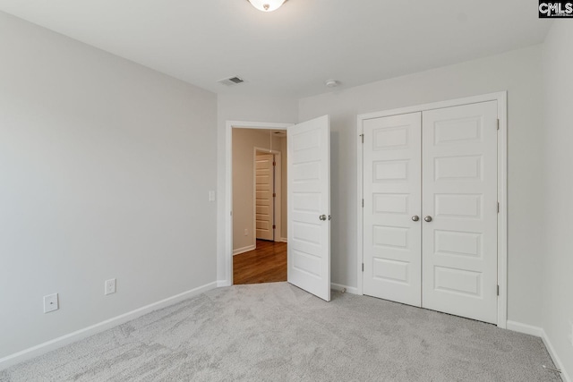 unfurnished bedroom with a closet and light carpet