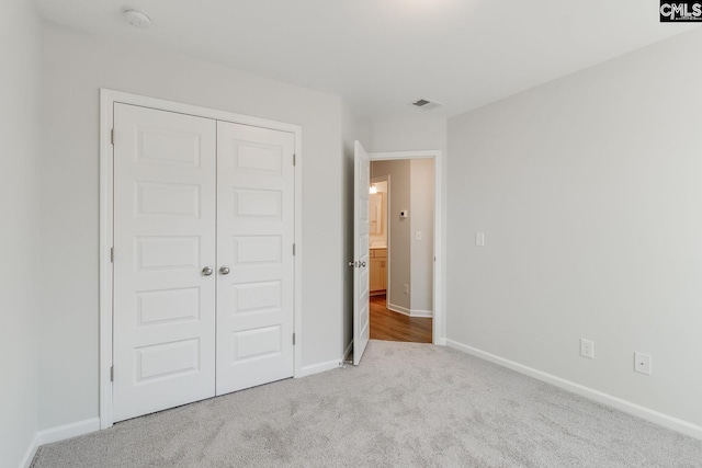 unfurnished bedroom with light carpet and a closet