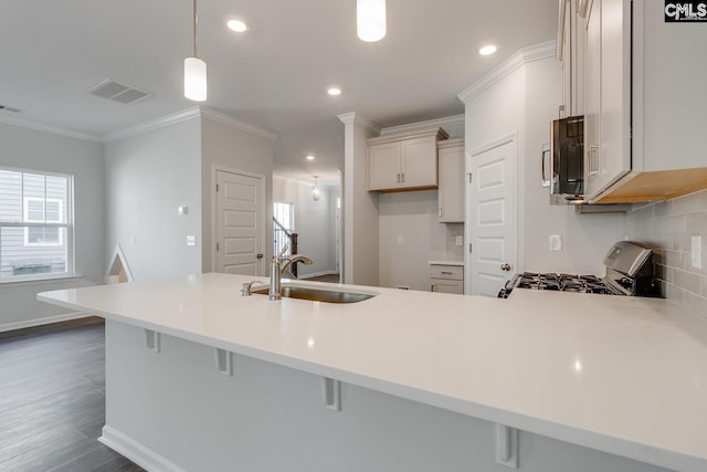 kitchen with decorative light fixtures, range with gas cooktop, kitchen peninsula, and a kitchen bar