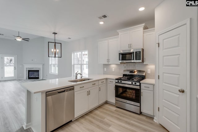 kitchen with sink, tasteful backsplash, kitchen peninsula, stainless steel appliances, and white cabinets