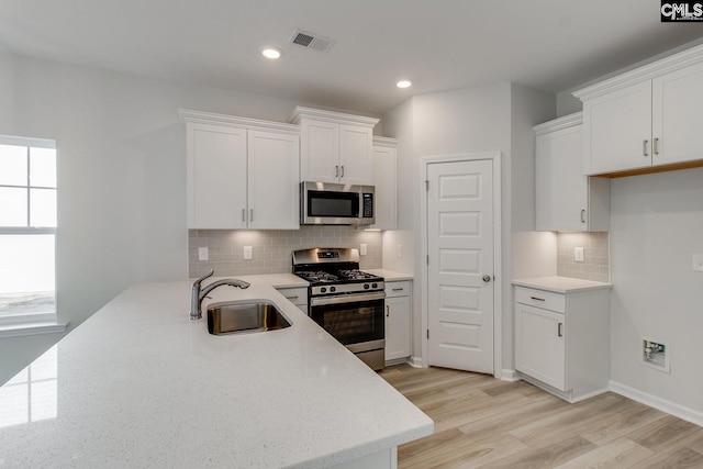 kitchen featuring light stone counters, sink, stainless steel appliances, and white cabinets