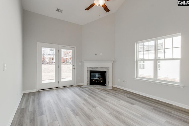 unfurnished living room with high vaulted ceiling, a fireplace, and light wood-type flooring