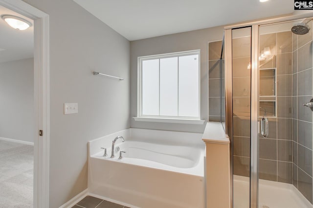 full bathroom featuring a stall shower, baseboards, a bath, and tile patterned floors