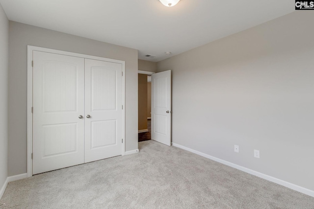 unfurnished bedroom with carpet floors, visible vents, baseboards, and a closet