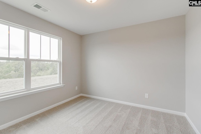 empty room featuring light carpet, visible vents, and baseboards