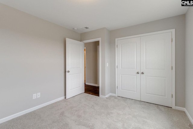 unfurnished bedroom featuring visible vents, a closet, baseboards, and carpet flooring