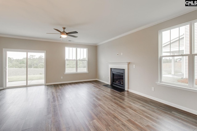 unfurnished living room with baseboards, wood finished floors, a fireplace with flush hearth, and crown molding