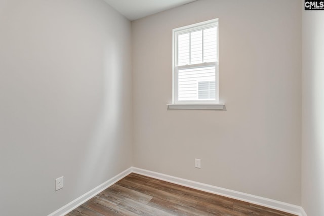 spare room with baseboards and wood finished floors