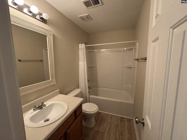 full bathroom featuring shower / bath combination with curtain, vanity, toilet, and a textured ceiling