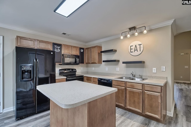 kitchen with a kitchen island, sink, ornamental molding, light hardwood / wood-style floors, and black appliances