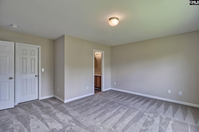 unfurnished bedroom with ensuite bathroom, carpet floors, and a closet