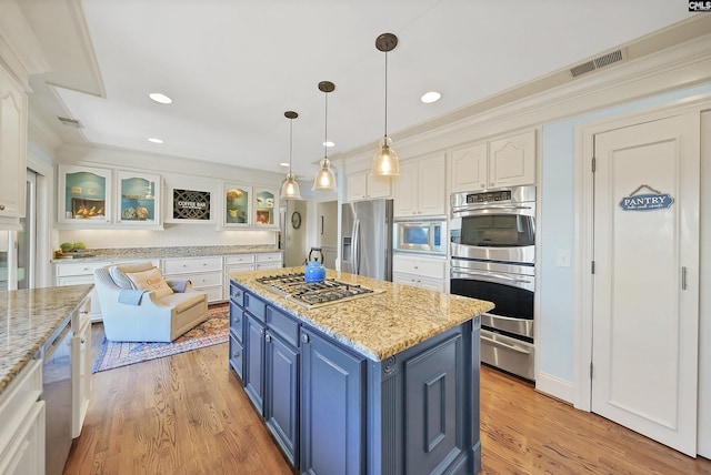 kitchen with blue cabinets, appliances with stainless steel finishes, white cabinets, and light stone counters