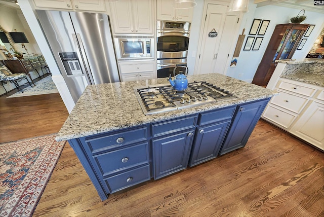 kitchen with white cabinetry, appliances with stainless steel finishes, blue cabinets, and a kitchen island with sink