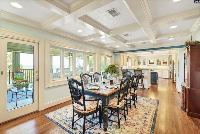 dining space featuring coffered ceiling, beam ceiling, crown molding, and light wood-type flooring