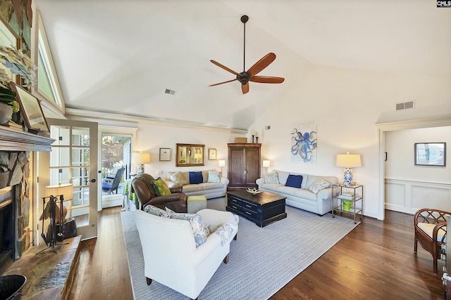 living room with a stone fireplace, dark wood-type flooring, lofted ceiling, and ceiling fan